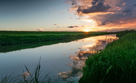 Sunset reflected on Seien River, flocked by long grass in Manitoba